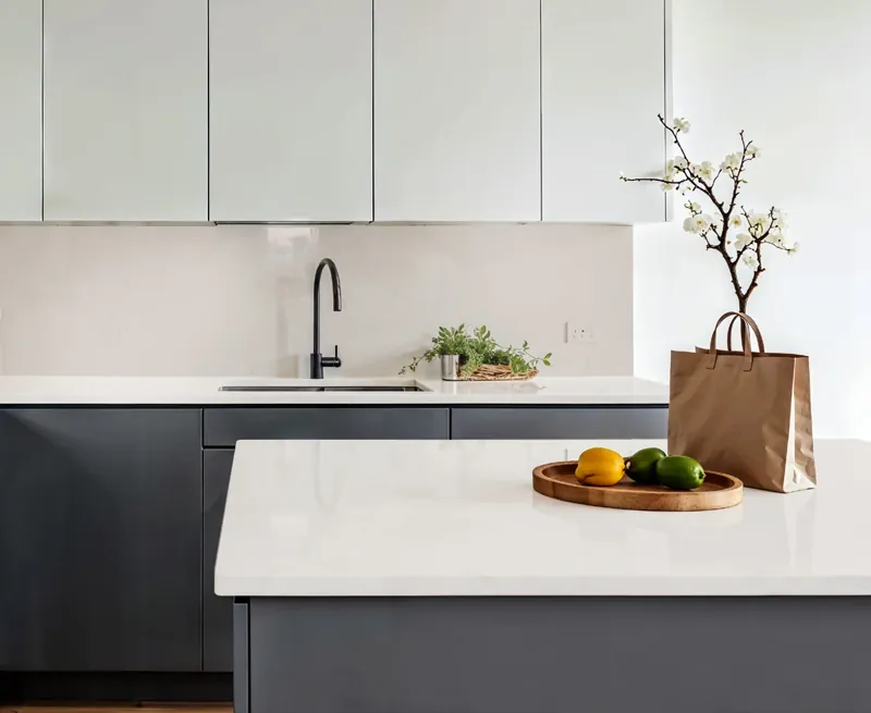 Jasny blat kuchenny solid surface z wyspą i grafitowymi szafkami
