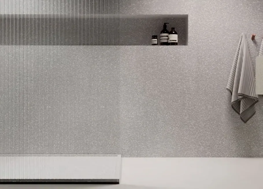 Ściana prysznica bez fug z HIMACS Terrazzo Grigio z wnęką na kosmetyki