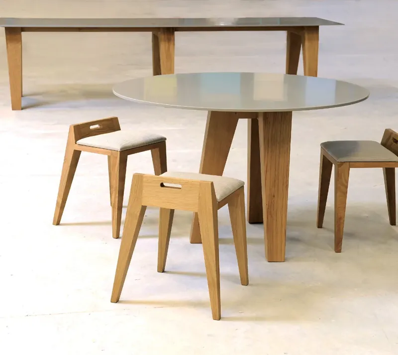 Okrągły stół z szarym blatem solid surface i drewniane taborety