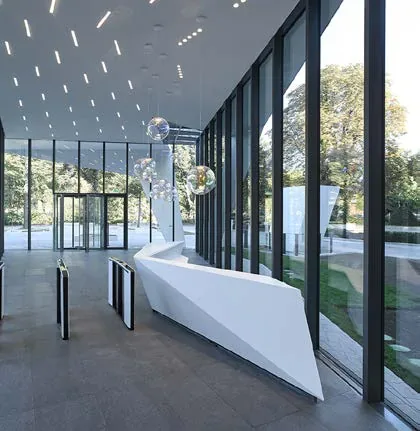 Foyer z rzeźbiarską białą ladą recepcyjną i sufitem z HIMACS