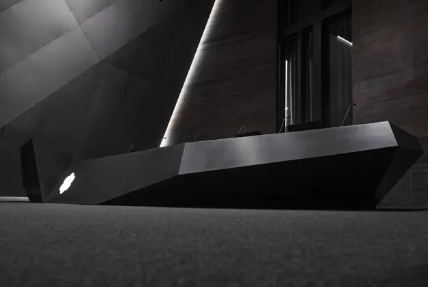 Monolityczny stół z ciemnego solid surface w sali wykładowej
