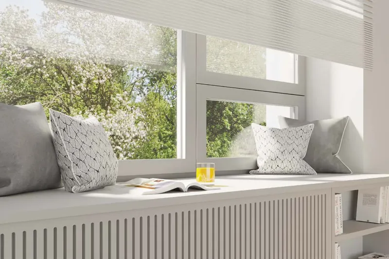 Biały parapet wewnętrzny laminowany z poduszkami przy oknie